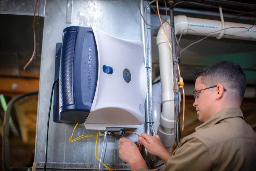 Airstream technician installing a whole-home humidifier on furnace ductwork